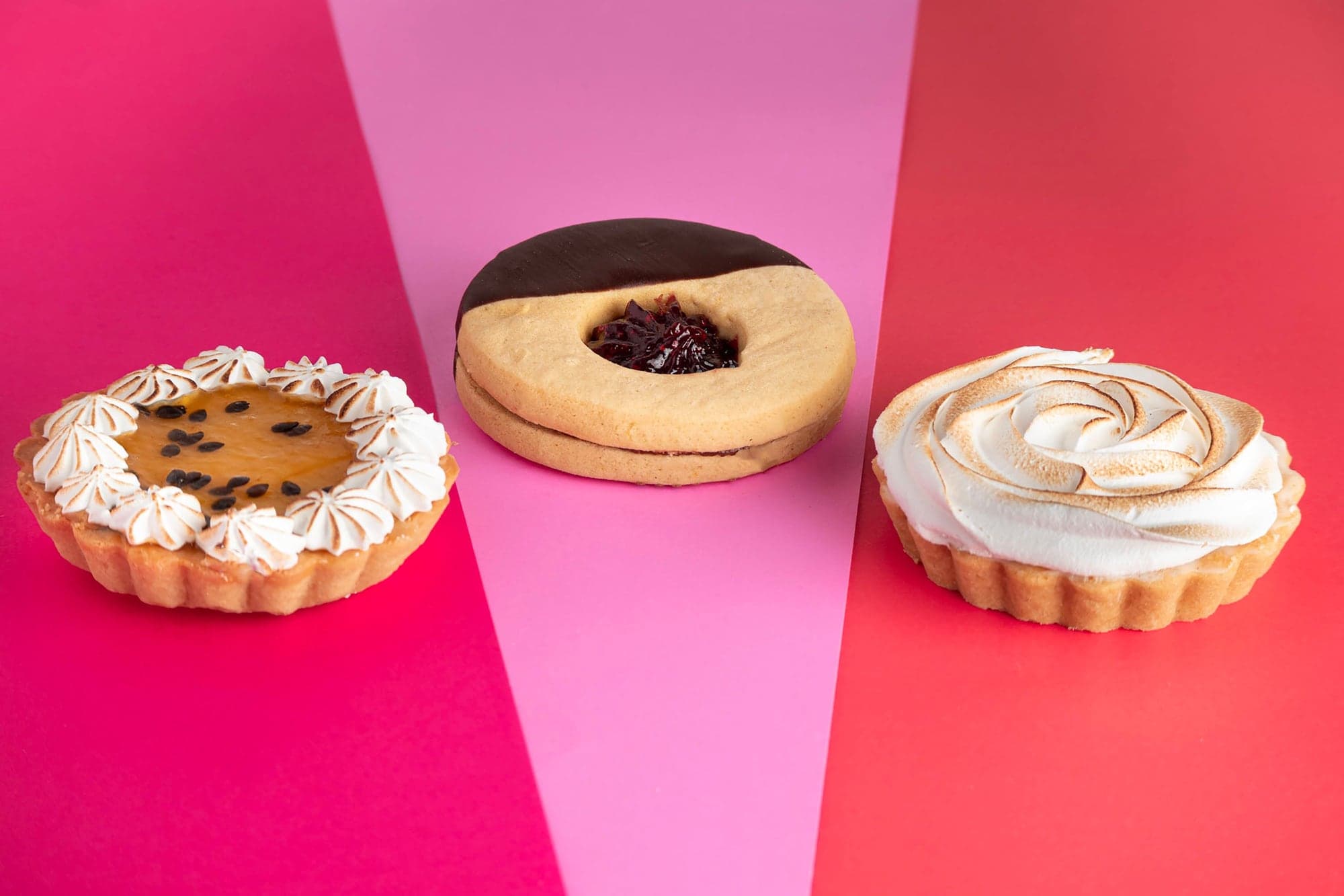Tres postres sobre fondo rosa y rojo