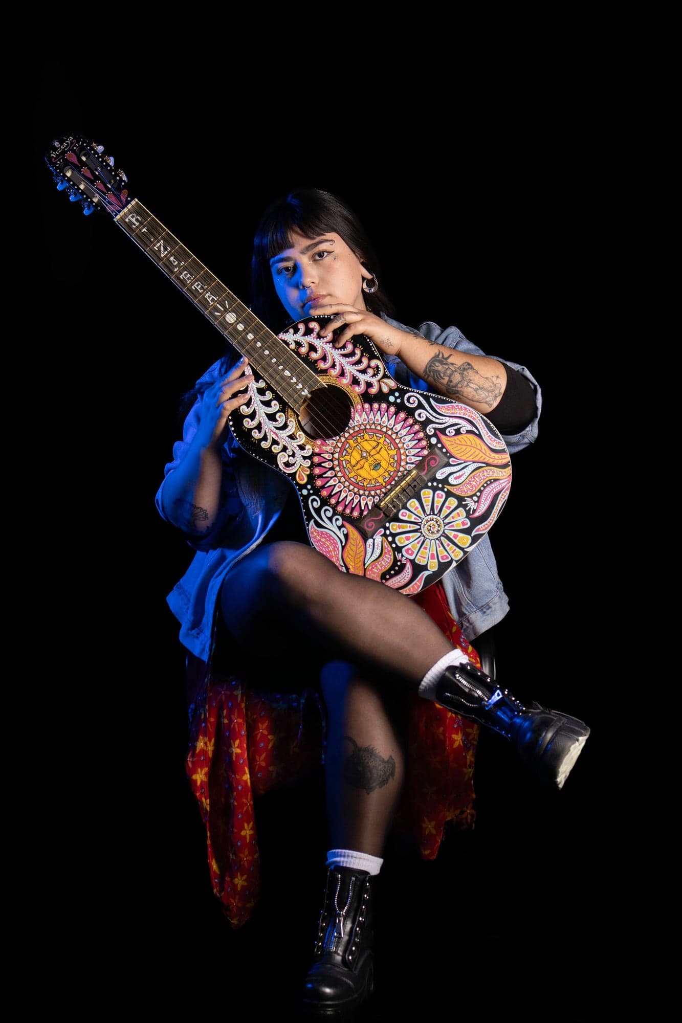 Vai sentada con su guitarra pintada a mano