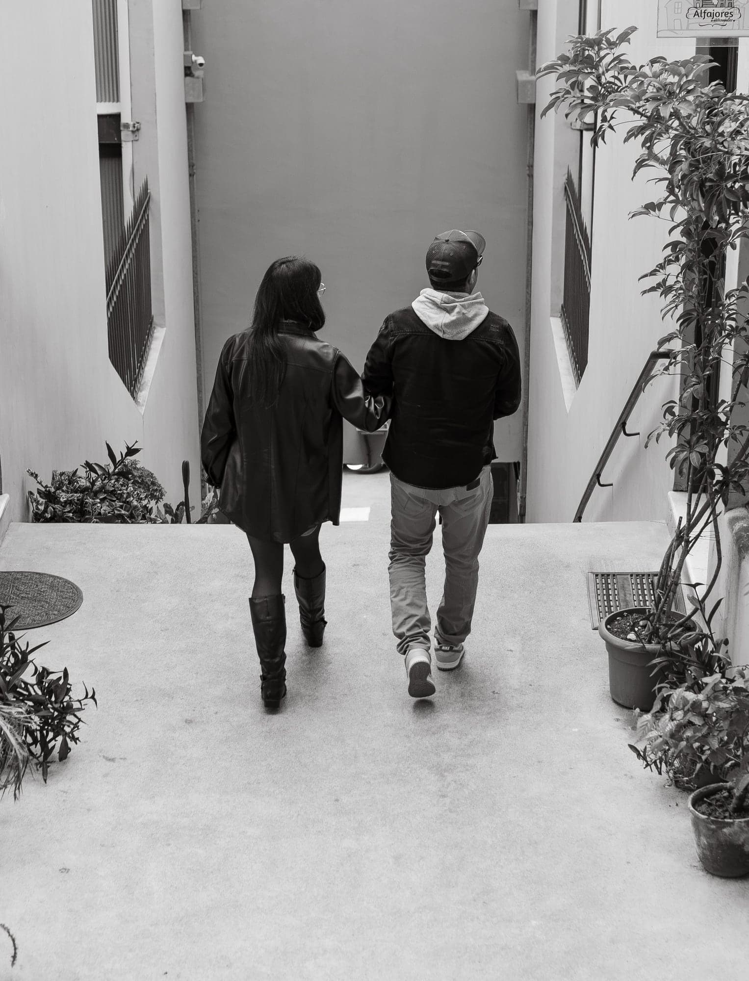 La pareja baja una escalera tomada del brazo, en blanco y negro