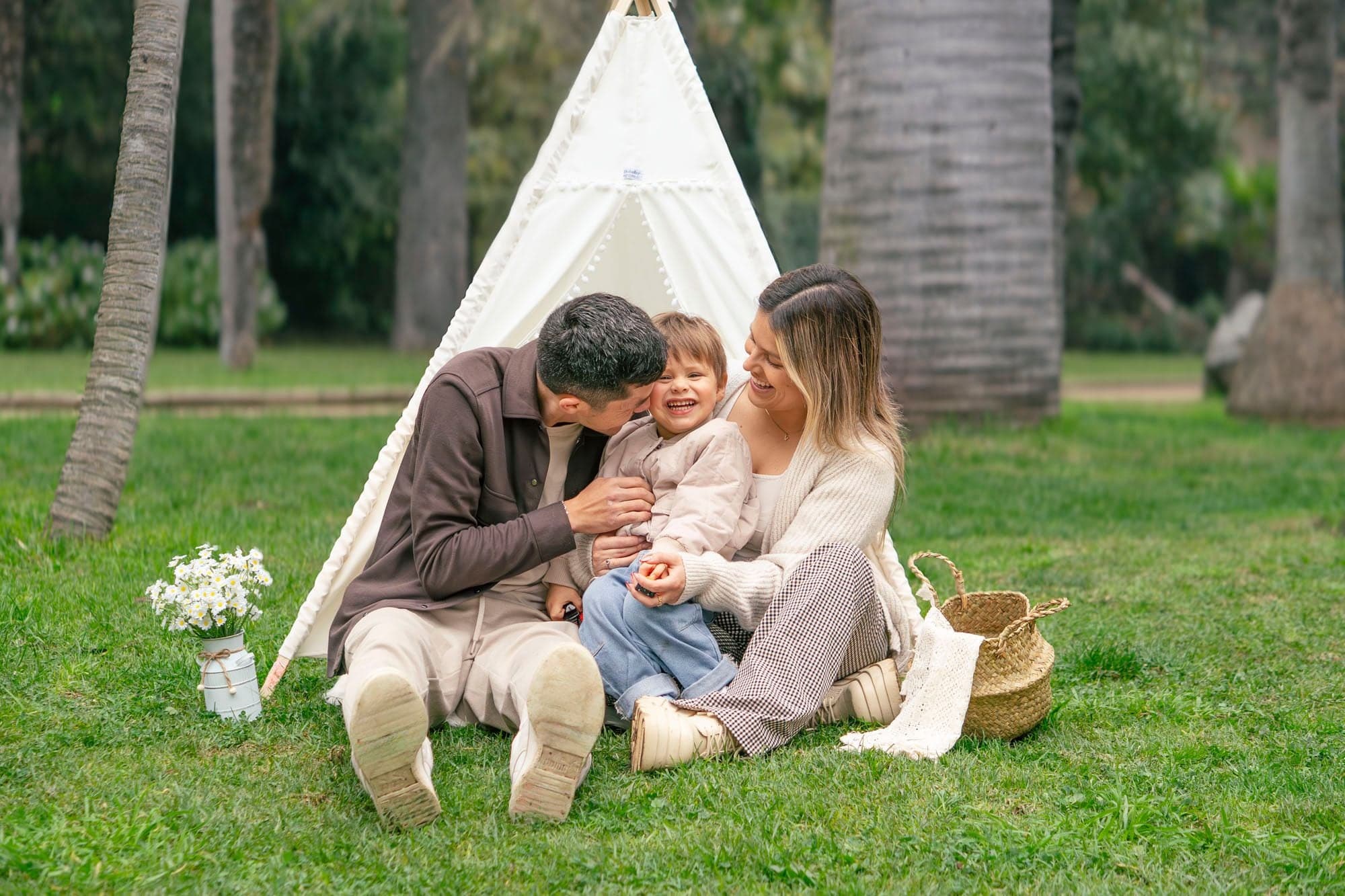 Valentino ríe con sus papás sentados frente al tipi